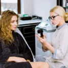 professional-cosmetologist-beauty-salon-consulting-young-beautiful-woman-grey-coat-showing-special-cream-skin-care-treatment-cosmetology-professional-skin-care-concept_161094-2495 (1)